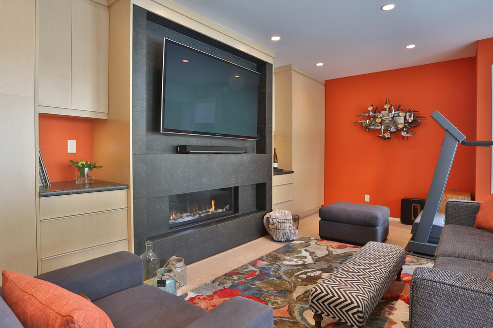 Inspiration pour un sous-sol design donnant sur l'extérieur et de taille moyenne avec un mur orange, une cheminée ribbon et un manteau de cheminée en pierre.