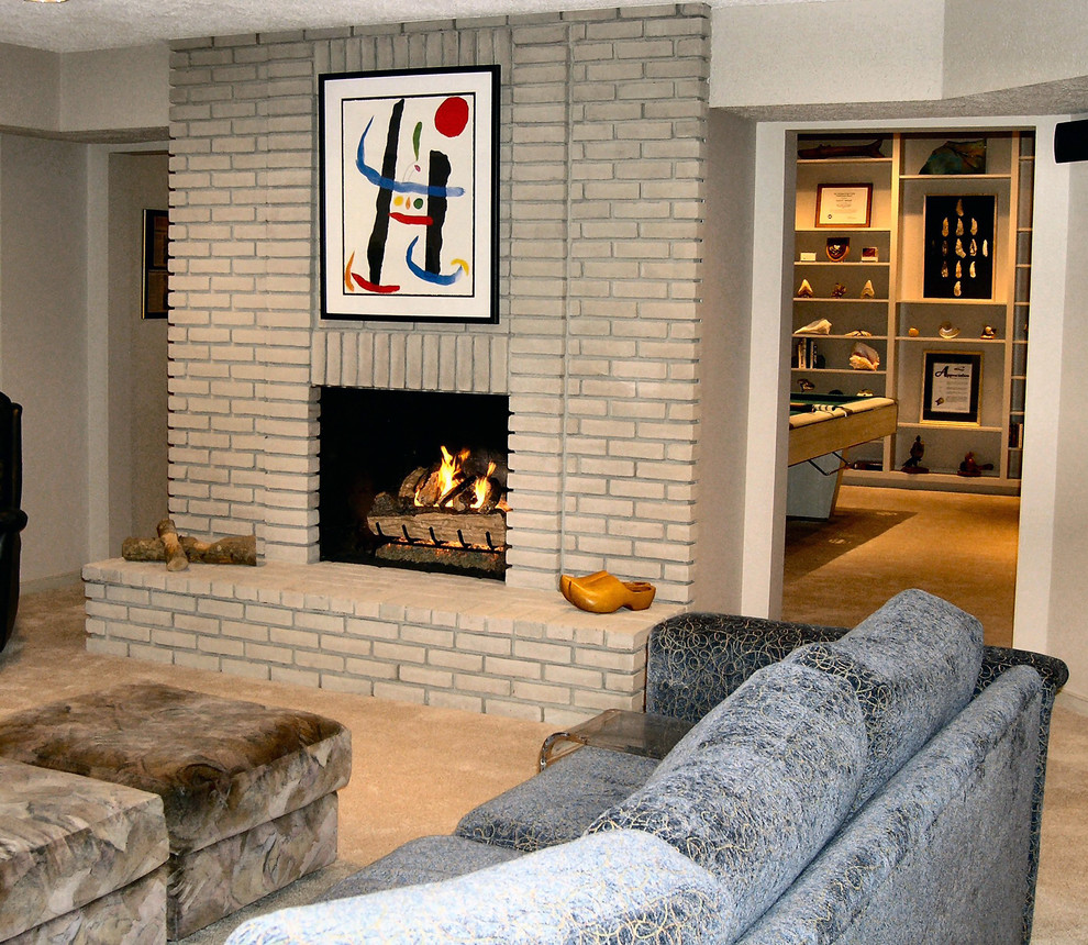 Mid-sized trendy look-out carpeted and beige floor basement photo in DC Metro with beige walls, a standard fireplace and a brick fireplace