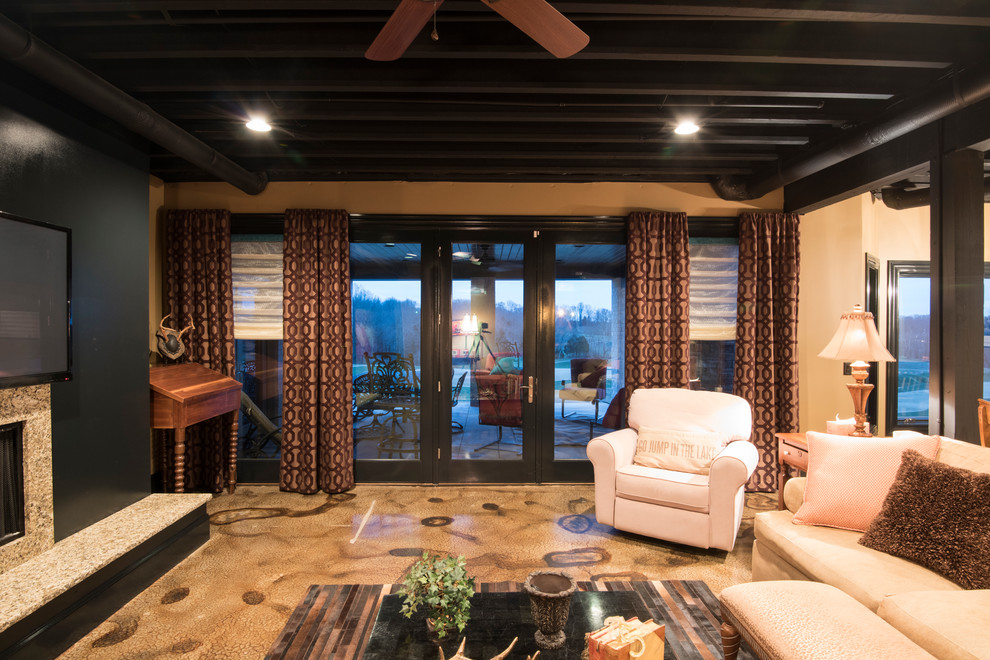 Cette image montre un grand sous-sol design donnant sur l'extérieur avec un mur beige, sol en béton ciré, une cheminée standard, un manteau de cheminée en carrelage et un sol beige.