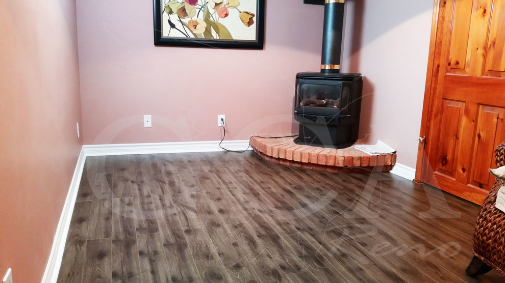 Example of a small mountain style underground medium tone wood floor basement design in Toronto with pink walls, a standard fireplace and a brick fireplace