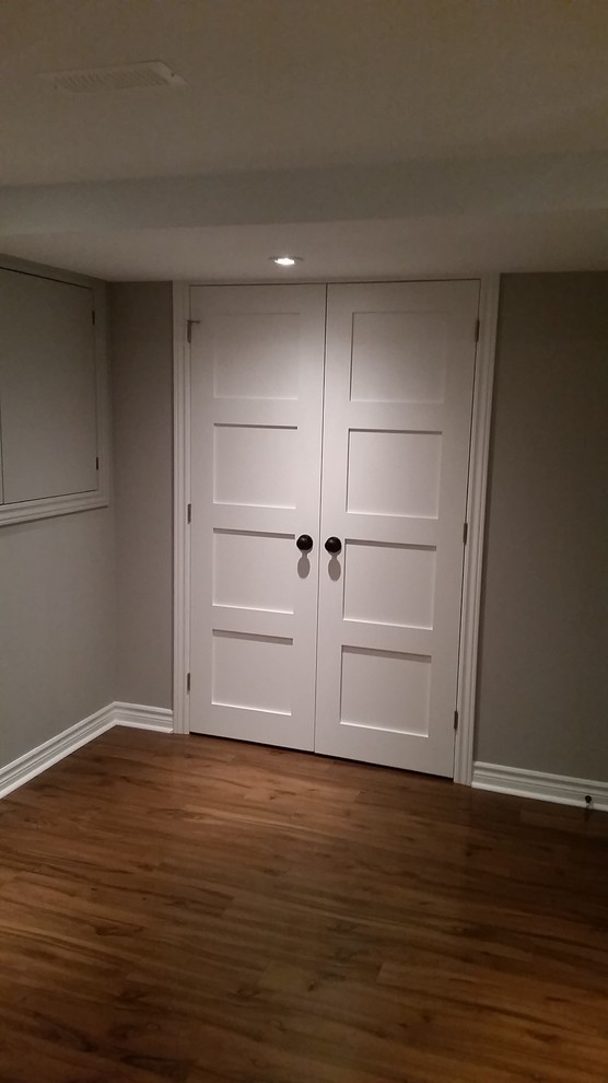Small contemporary fully buried basement in Ottawa with grey walls and medium hardwood flooring.