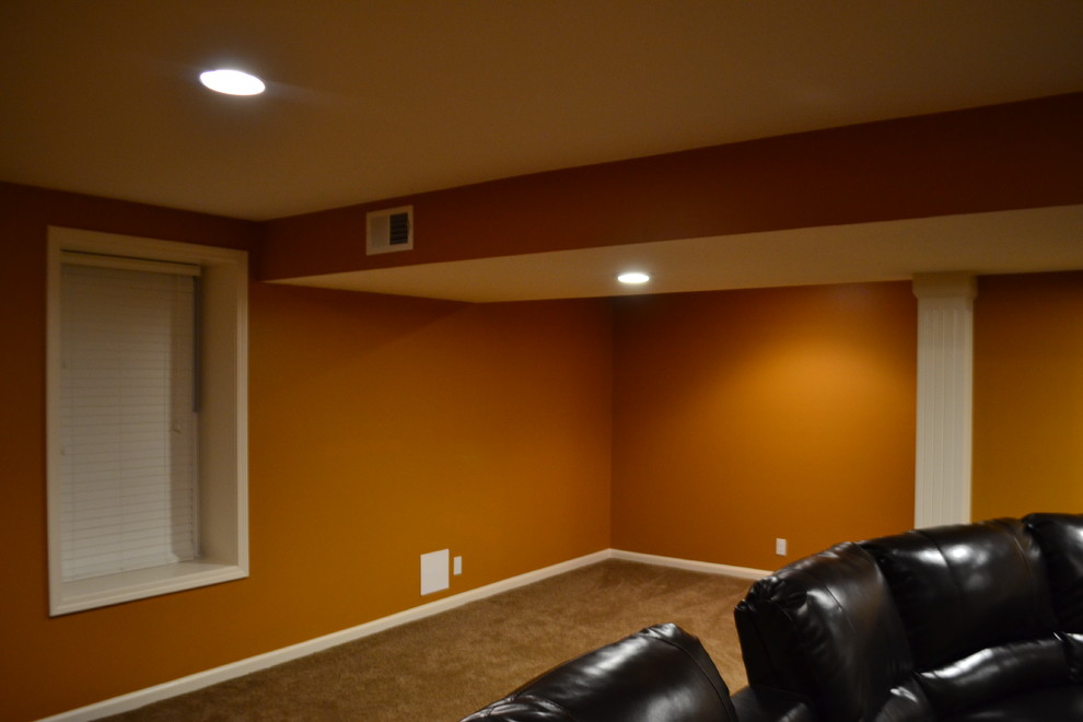 This is an example of a large traditional home cinema in Kansas City with orange walls, carpet and brown floors.