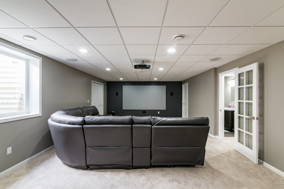 Modelo de cine en casa moderno grande con paredes grises, moqueta y suelo beige
