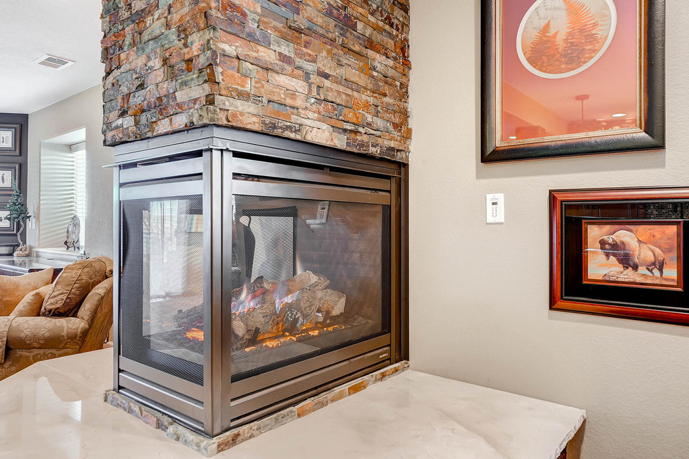 Medium sized classic walk-out basement in Denver with beige walls, light hardwood flooring, a two-sided fireplace and a stone fireplace surround.