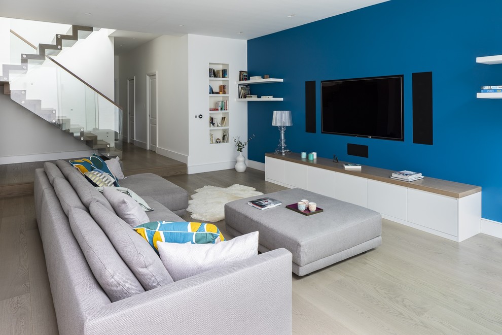 Immagine di un grande soggiorno minimal con pareti blu, pavimento in legno massello medio, nessun camino e pavimento marrone