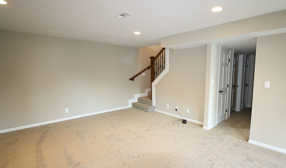 Aménagement d'un grand sous-sol classique donnant sur l'extérieur avec un mur beige et moquette.