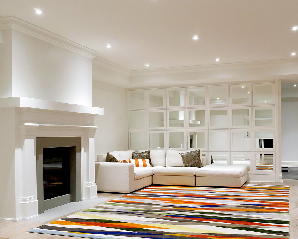 Großes Modernes Untergeschoss mit weißer Wandfarbe, hellem Holzboden, Kamin und Kaminumrandung aus Stein in Toronto