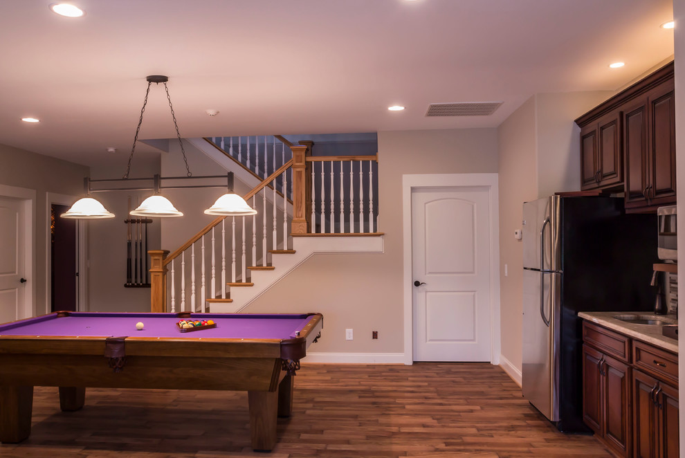 This is an example of a large traditional walk-out basement in Other with beige walls, medium hardwood flooring, a standard fireplace and a stone fireplace surround.