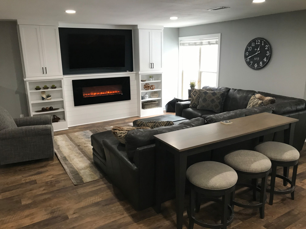 Inspiration for a mid-sized transitional walk-out vinyl floor and brown floor basement remodel in Milwaukee with gray walls, a ribbon fireplace and a wood fireplace surround