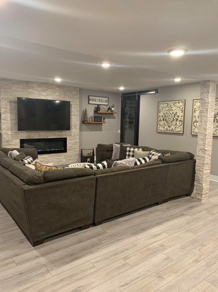Inspiration for a medium sized modern fully buried basement in Denver with grey walls, vinyl flooring, a hanging fireplace, a stone fireplace surround and grey floors.