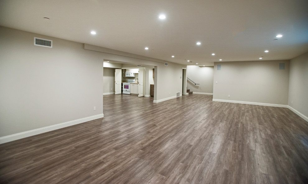 Inspiration for a large contemporary fully buried basement in Los Angeles with beige walls, medium hardwood flooring and no fireplace.