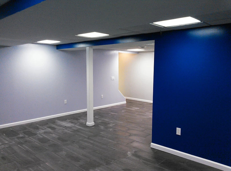 Modern inredning av en mellanstor källare utan fönster, med blå väggar, skiffergolv och grått golv
