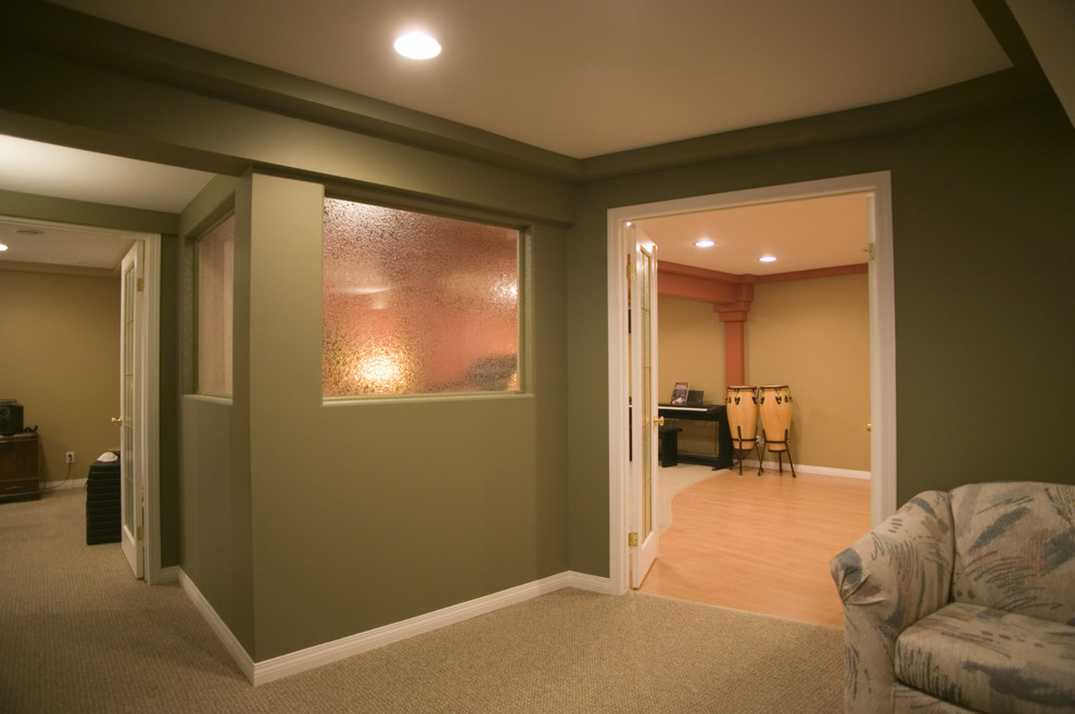Cette photo montre un grand sous-sol tendance semi-enterré avec un mur vert et parquet clair.