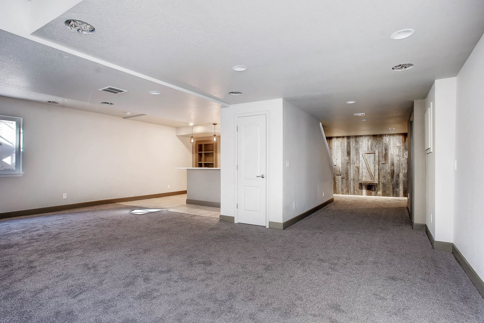 Mittelgroßes Industrial Untergeschoss mit weißer Wandfarbe, Teppichboden, grauem Boden, Kamin und Kaminumrandung aus Holz in Denver