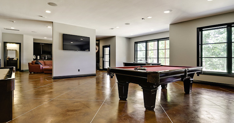 This is an example of a medium sized traditional walk-out basement in Other with white walls, concrete flooring and brown floors.