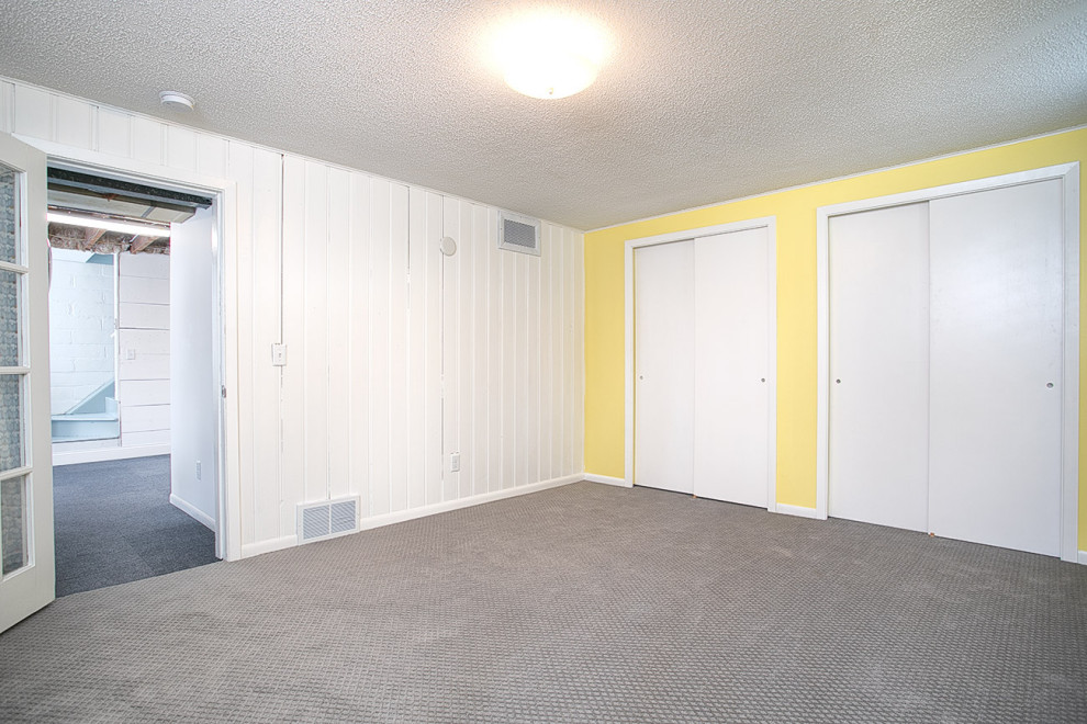 ミネアポリスにあるお手頃価格の中くらいなミッドセンチュリースタイルのおしゃれな地下室 (半地下 (窓あり) 、黄色い壁、カーペット敷き、グレーの床、塗装板張りの壁) の写真