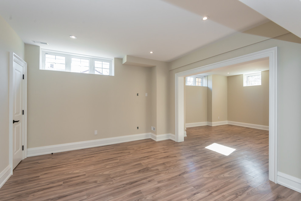 This is an example of a medium sized classic walk-out basement in Toronto with beige walls, medium hardwood flooring, no fireplace and brown floors.