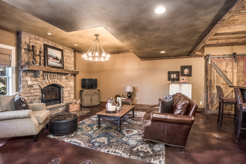 Example of a large mountain style walk-out concrete floor and brown floor basement design in Kansas City with beige walls, a standard fireplace and a stone fireplace