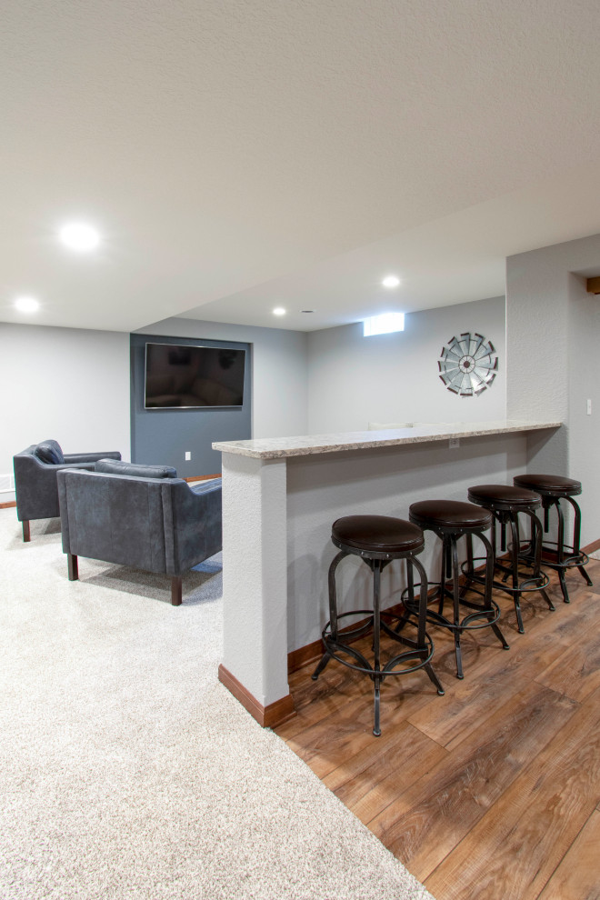 Photo of an expansive traditional fully buried basement in Milwaukee with a home bar, grey walls, carpet, beige floors, exposed beams and wood walls.