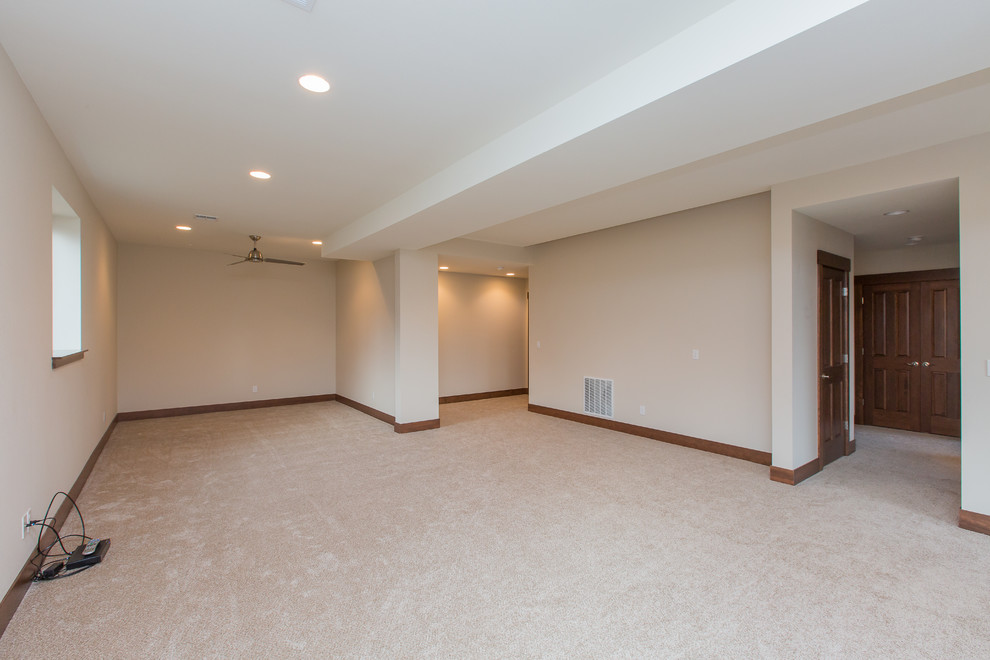 This is an example of a large modern walk-out basement in Portland with beige walls and carpet.