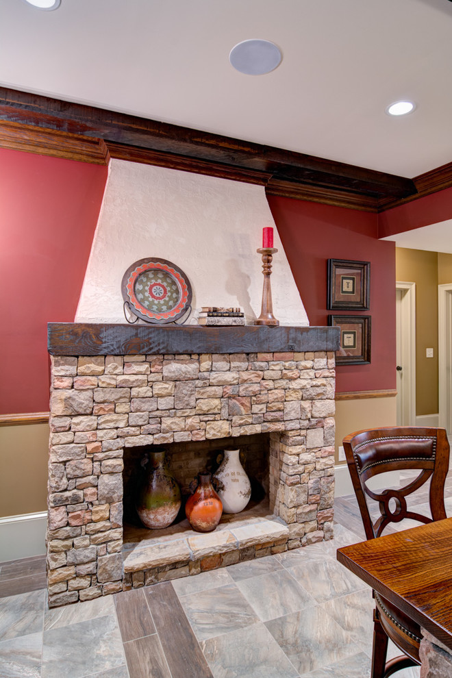 Aménagement d'un grand sous-sol classique donnant sur l'extérieur avec un mur marron, un sol en carrelage de porcelaine, une cheminée standard et un manteau de cheminée en pierre.