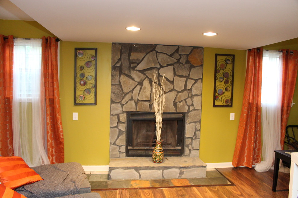 Exemple d'un sous-sol sud-ouest américain avec un mur vert, un sol en bois brun, une cheminée standard et un manteau de cheminée en pierre.
