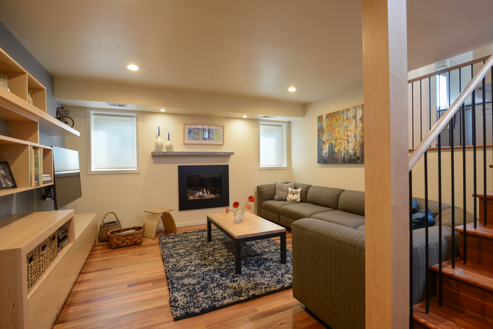 This is an example of a small modern basement in Denver with yellow walls, medium hardwood flooring and a standard fireplace.