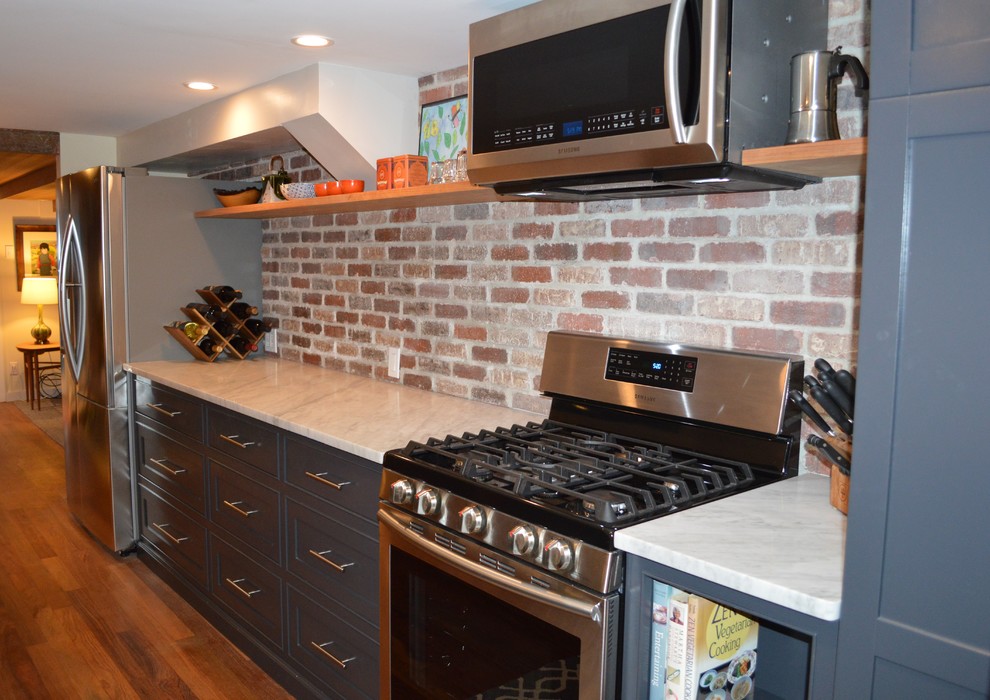 Cette photo montre une cuisine parallèle chic de taille moyenne avec un évier 2 bacs, des portes de placard grises, plan de travail en marbre et un électroménager en acier inoxydable.