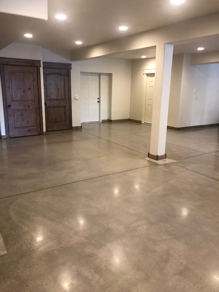 Cette photo montre un grand sous-sol moderne avec sol en béton ciré et un sol gris.