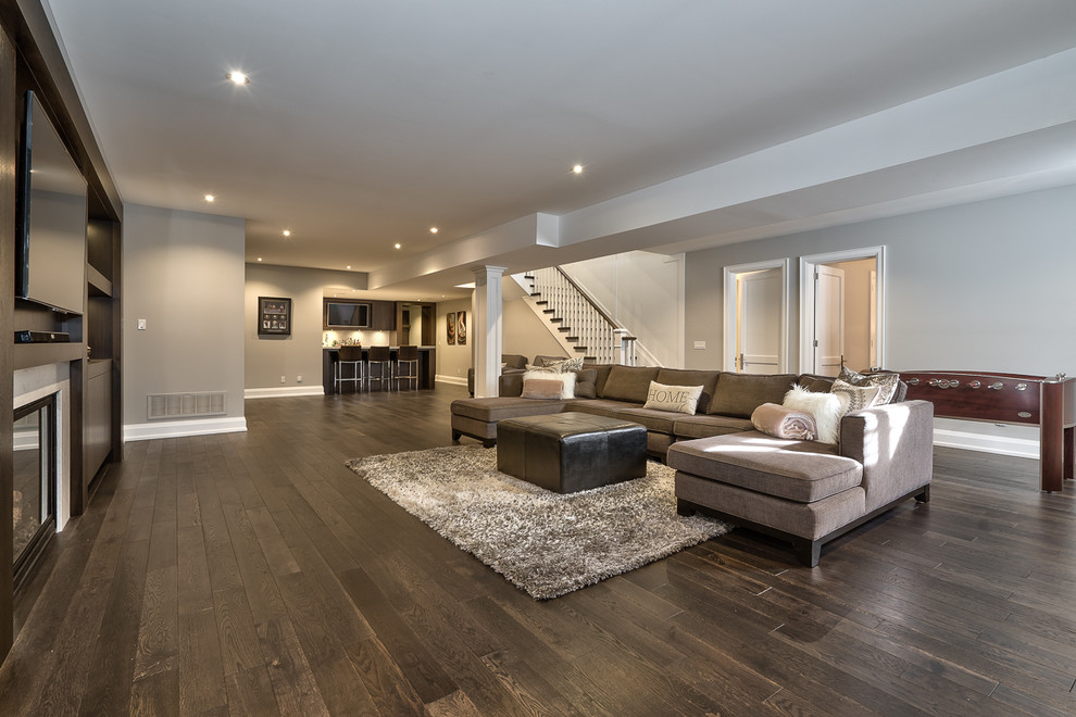 Design ideas for an expansive contemporary basement in Toronto with grey walls, dark hardwood flooring and a standard fireplace.