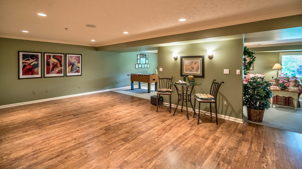 This is an example of a medium sized eclectic walk-out basement in Other with green walls and light hardwood flooring.