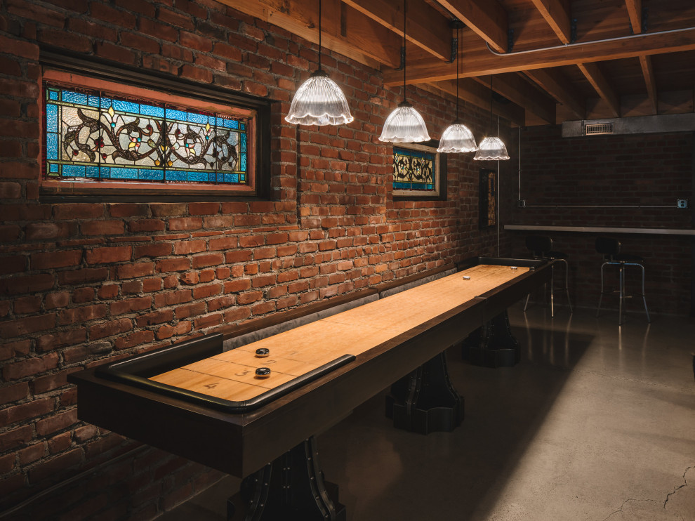 Inspiration for a large industrial walk-out basement in Portland with a home bar, multi-coloured walls, concrete flooring, a standard fireplace, a brick fireplace surround, grey floors, exposed beams and brick walls.