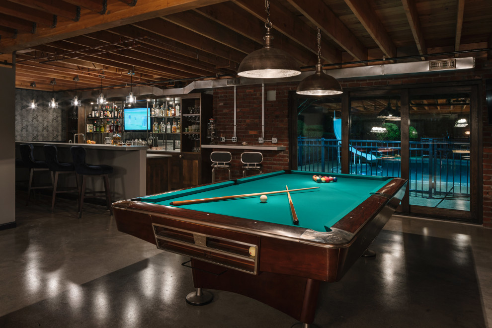 Large industrial walk-out basement in Portland with a home bar, multi-coloured walls, concrete flooring, a standard fireplace, a brick fireplace surround, grey floors, exposed beams and brick walls.
