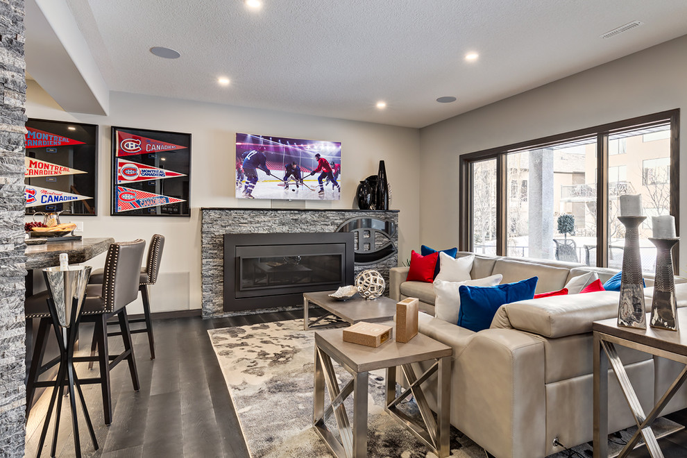Design ideas for a large traditional walk-out basement in Calgary with grey walls, medium hardwood flooring, a standard fireplace, a stone fireplace surround and grey floors.