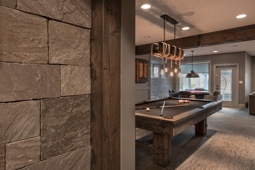 Inspiration for a large contemporary walk-out basement in Edmonton with a game room, grey walls, carpet, a standard fireplace, a brick fireplace surround, brown floors, exposed beams and panelled walls.