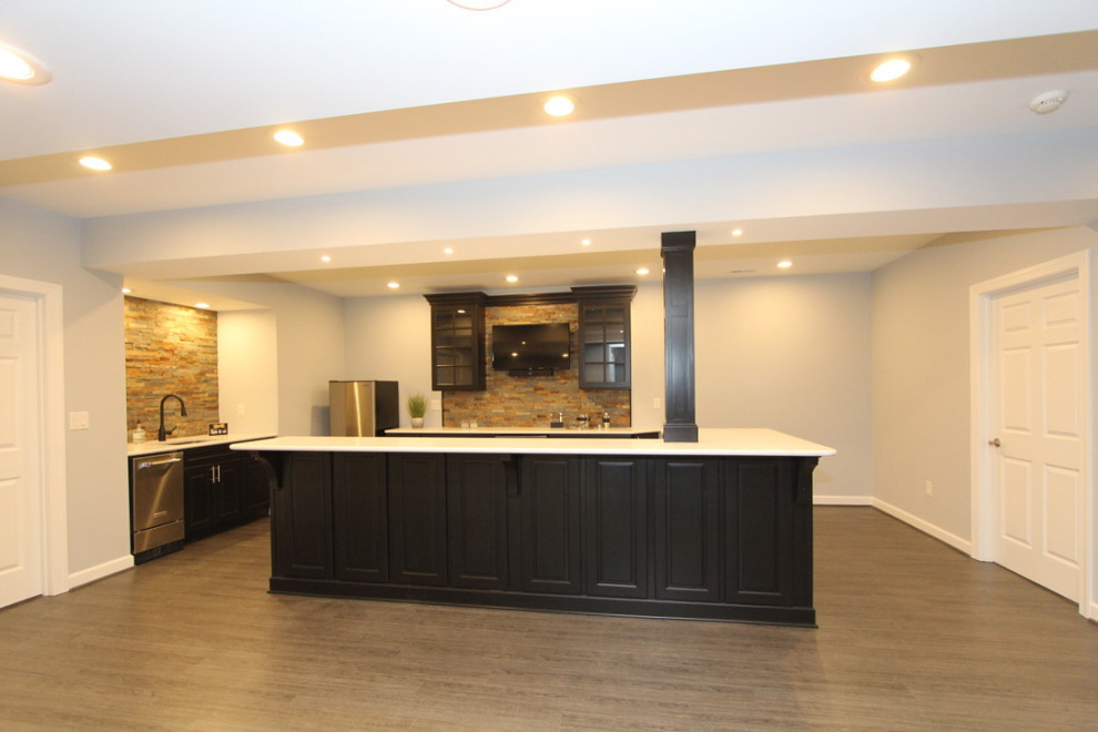 This is an example of a large classic walk-out basement in Baltimore with a home bar, grey walls, vinyl flooring and brown floors.