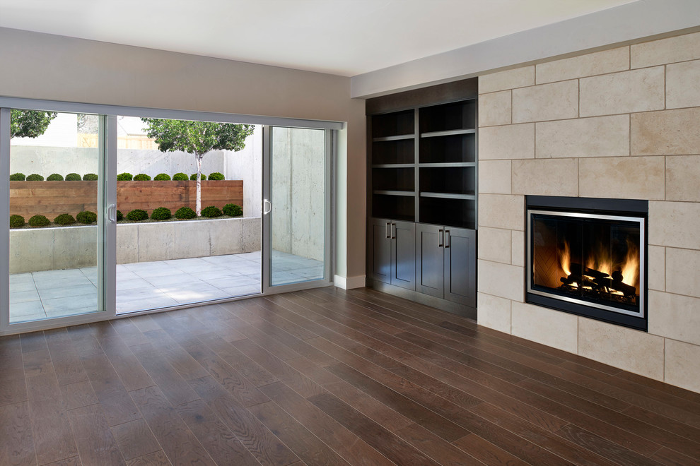 Exemple d'un sous-sol tendance donnant sur l'extérieur et de taille moyenne avec un sol en bois brun, une cheminée standard et un manteau de cheminée en pierre.