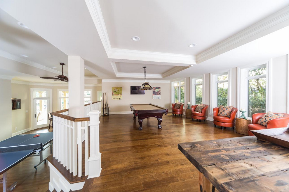 Large transitional walk-out medium tone wood floor, brown floor and tray ceiling basement game room photo in Charlotte with beige walls and no fireplace