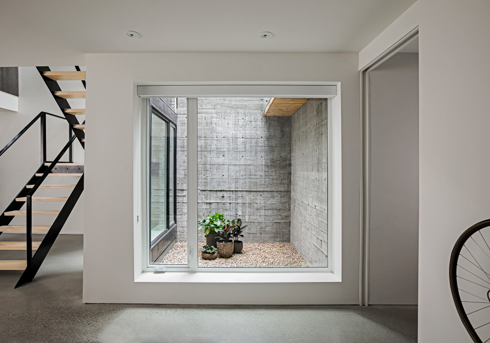 Mittelgroßes Modernes Untergeschoss mit weißer Wandfarbe, Betonboden und grauem Boden in Calgary
