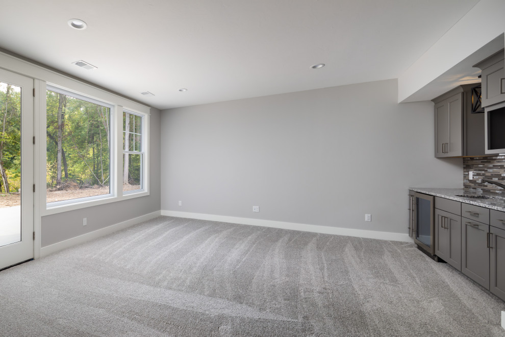 Inspiration for a mid-sized craftsman walk-out carpeted and gray floor basement remodel in Grand Rapids with gray walls