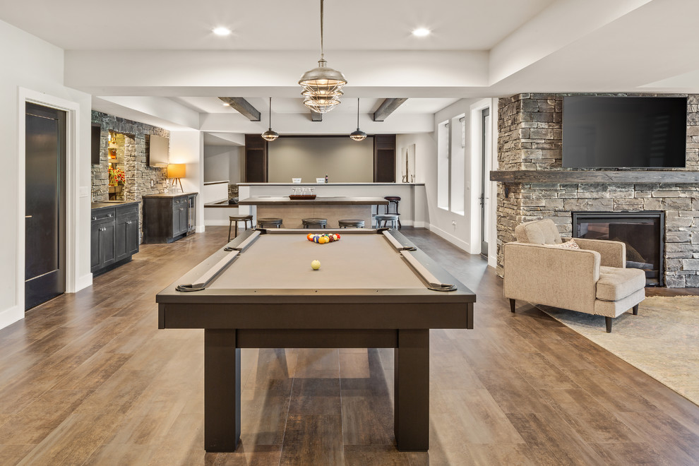 Photo of a large farmhouse games room in Cincinnati with white walls, vinyl flooring, a standard fireplace, a stone fireplace surround, brown floors and a game room.