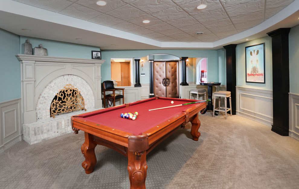 Design ideas for a large classic fully buried basement in Chicago with a game room, blue walls, carpet, a corner fireplace, a brick fireplace surround, beige floors, a drop ceiling and panelled walls.