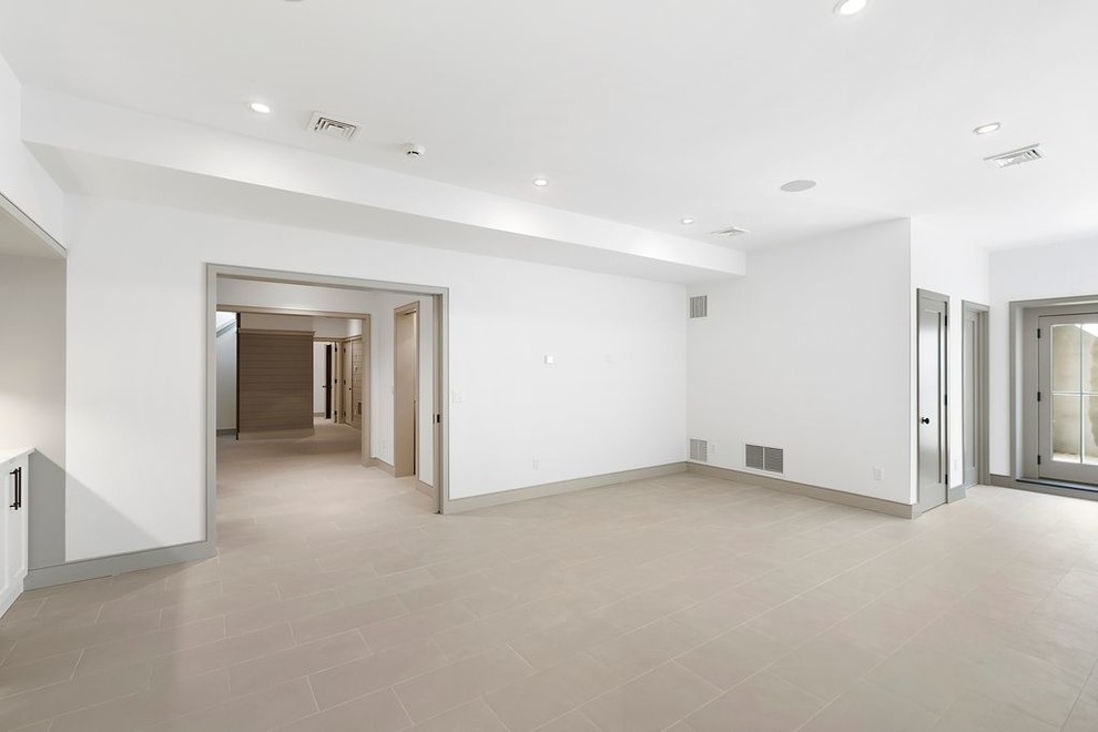 This is an example of an expansive contemporary walk-out basement in Burlington with white walls, travertine flooring and grey floors.