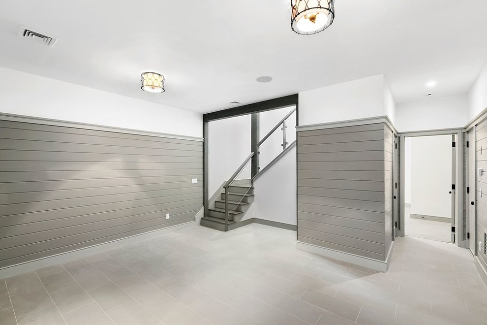 Cette image montre un très grand sous-sol design donnant sur l'extérieur avec un mur blanc, un sol en travertin et un sol gris.