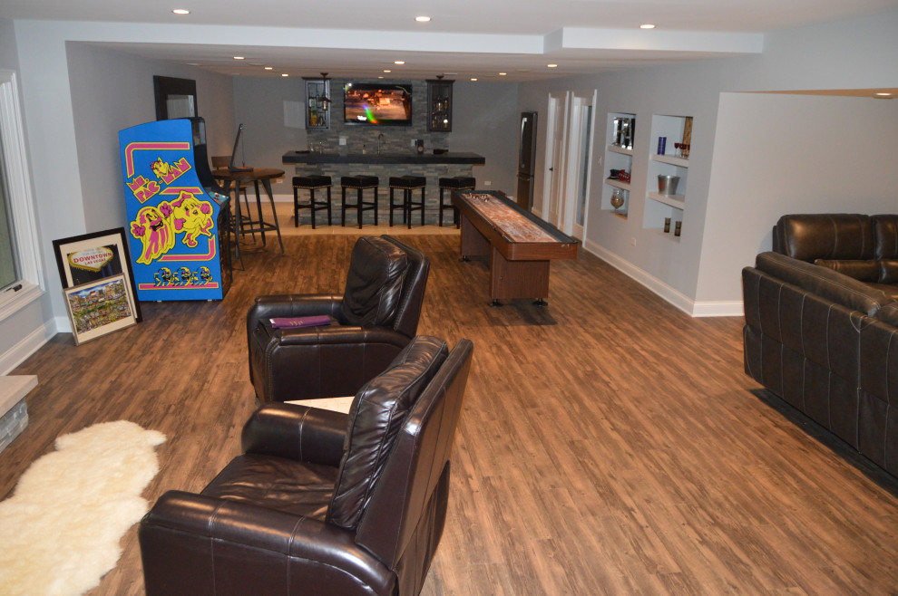 Mid-sized transitional walk-out medium tone wood floor and brown floor basement photo in Chicago with gray walls, a standard fireplace and a stone fireplace
