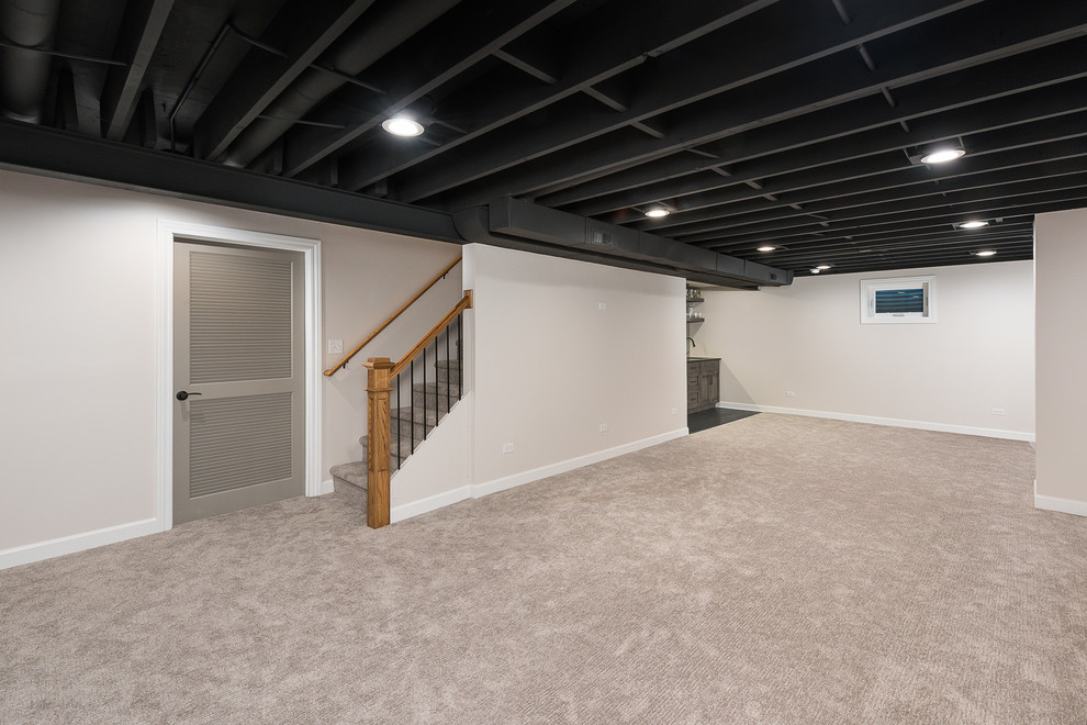 Photo of a large classic fully buried basement in Chicago with white walls, carpet, no fireplace and white floors.