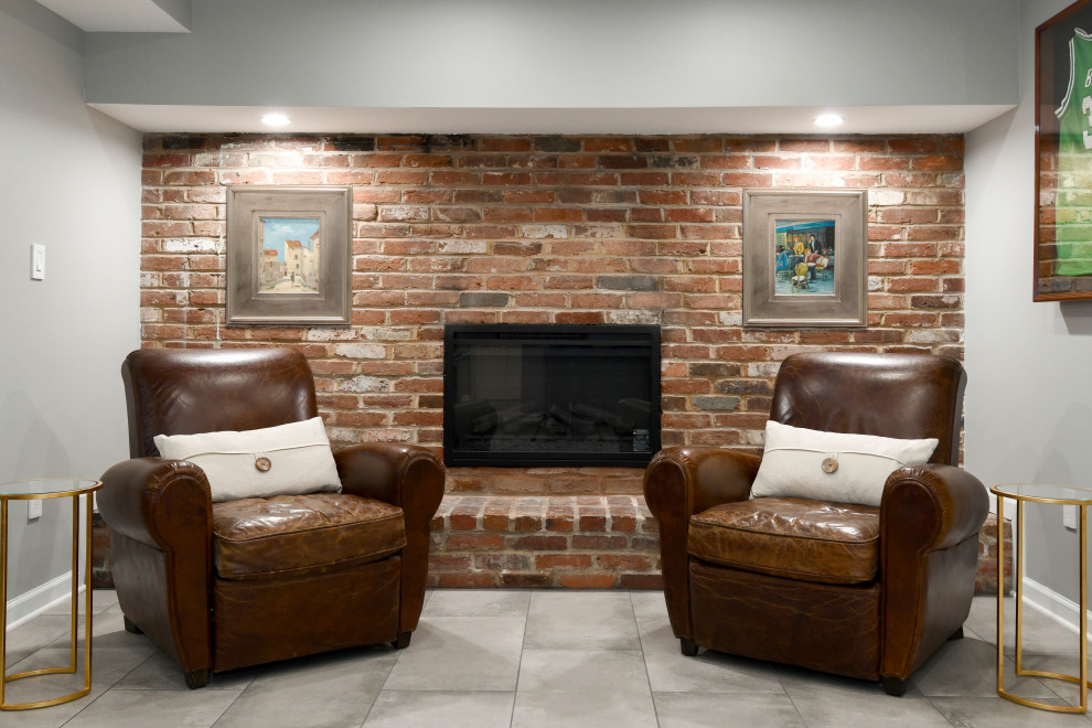 Cette image montre un grand sous-sol traditionnel avec un bar de salon, un mur gris, un sol en carrelage de porcelaine, une cheminée standard, un manteau de cheminée en brique et un sol gris.
