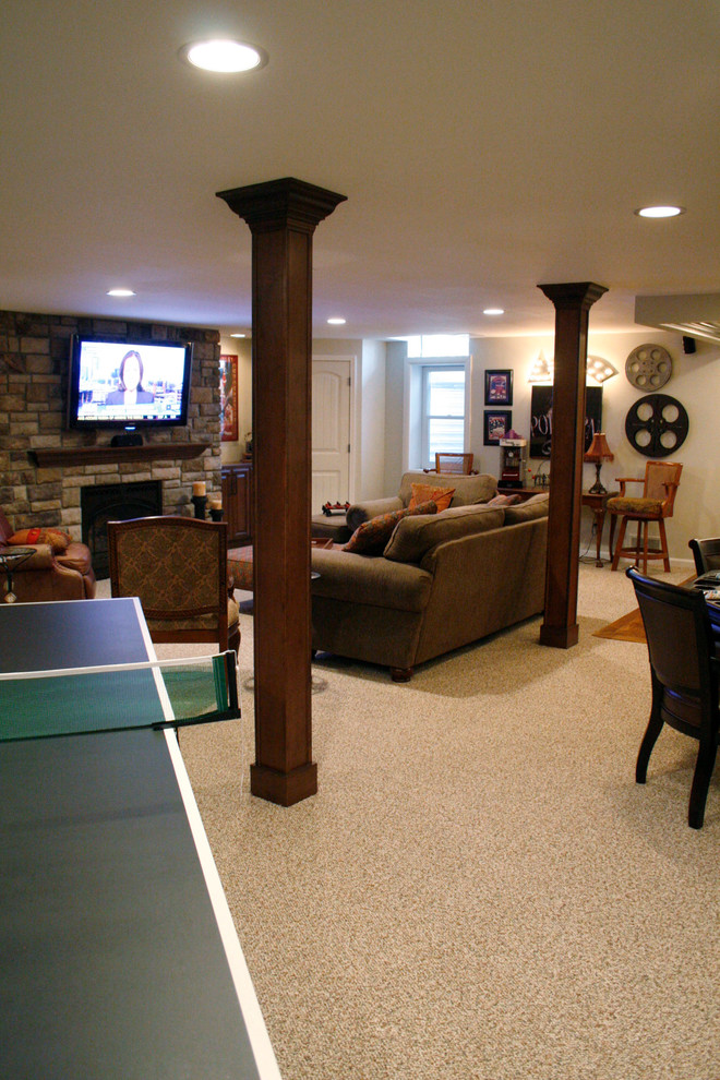 Huge trendy underground carpeted basement photo in Detroit with beige walls, a standard fireplace and a stone fireplace