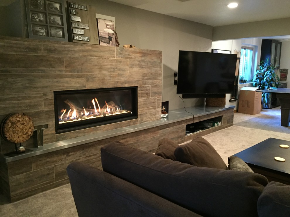 Example of a large trendy walk-out carpeted and beige floor basement design in Denver with beige walls, a ribbon fireplace and a tile fireplace