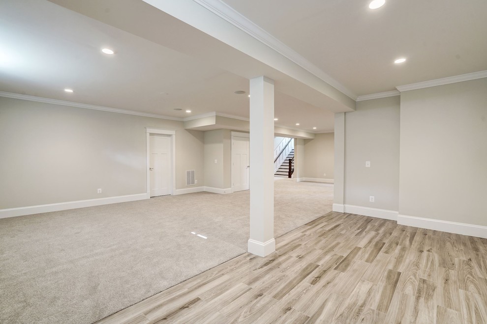 This is an example of a large country walk-out basement in DC Metro with beige walls, carpet, no fireplace and brown floors.